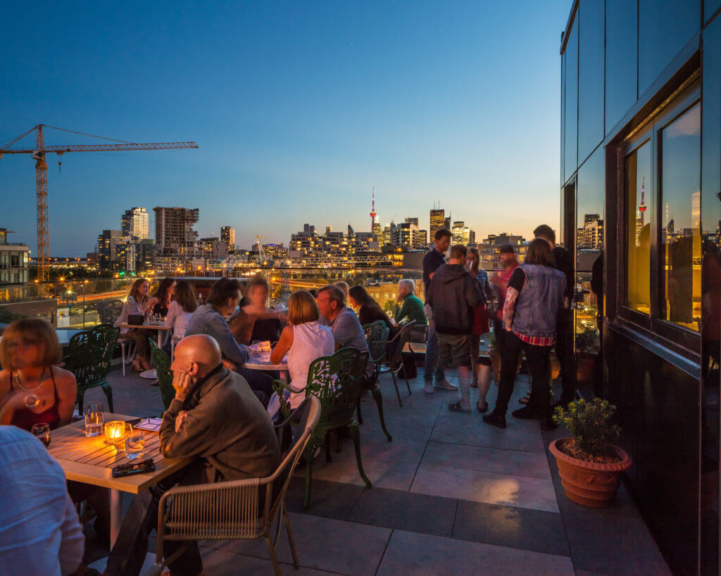 Dusk time photo of people eating on the rooftop restaurant at The Broadview Hotel