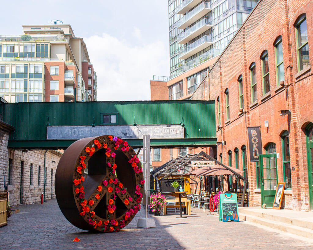 Photo of large peace sign installation that is covered in flowers at The Distillery District