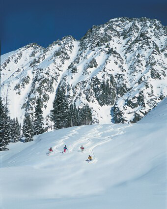 Photo of people snowboarding down the side of the mountain Arapahoe Basin