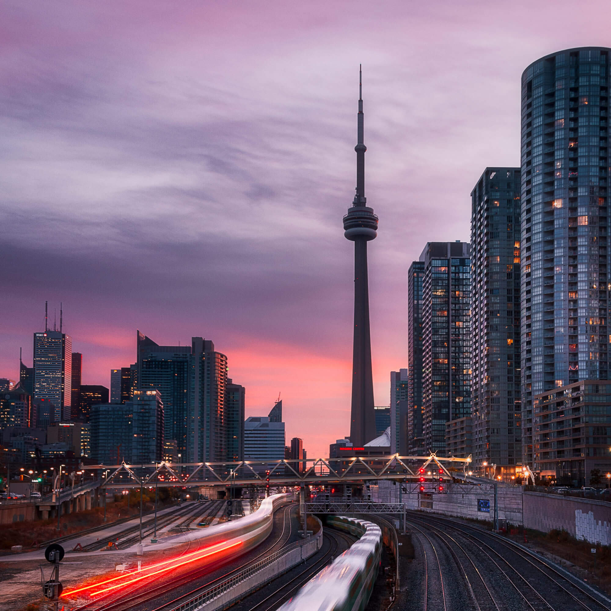 Sunset in downtown Toronto including the CN tower, tall glass buildings and the GO train
