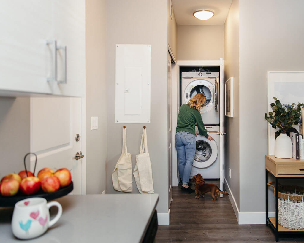 Photo of woman in the laundry room checking the dryer Brighton Village Rentals