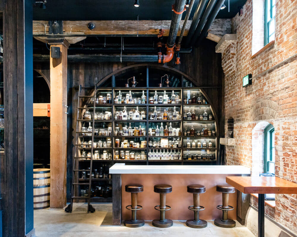 Inside of Spirit of York distillery bartop with stools and bottles behind