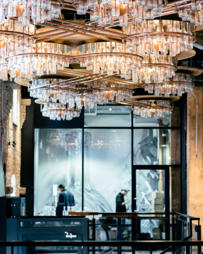 Inside view of the Spirit of York distillery including people working and a large chandelier