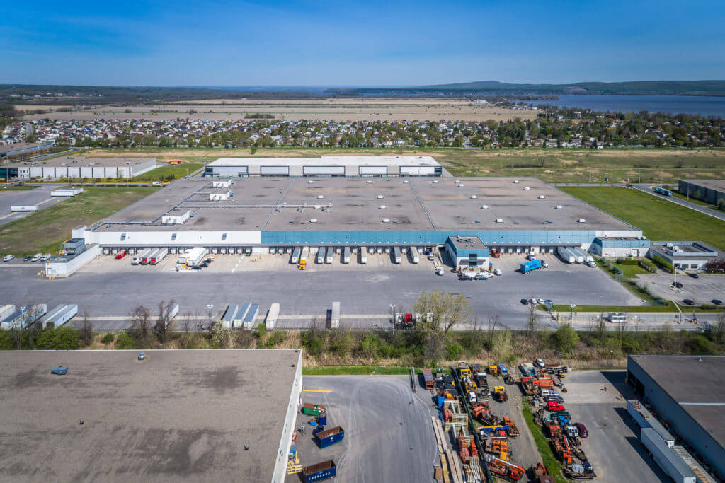 Aerial image of Dream Industrial Warehouse Building in Montreal, QC with blue skies and water in the background.