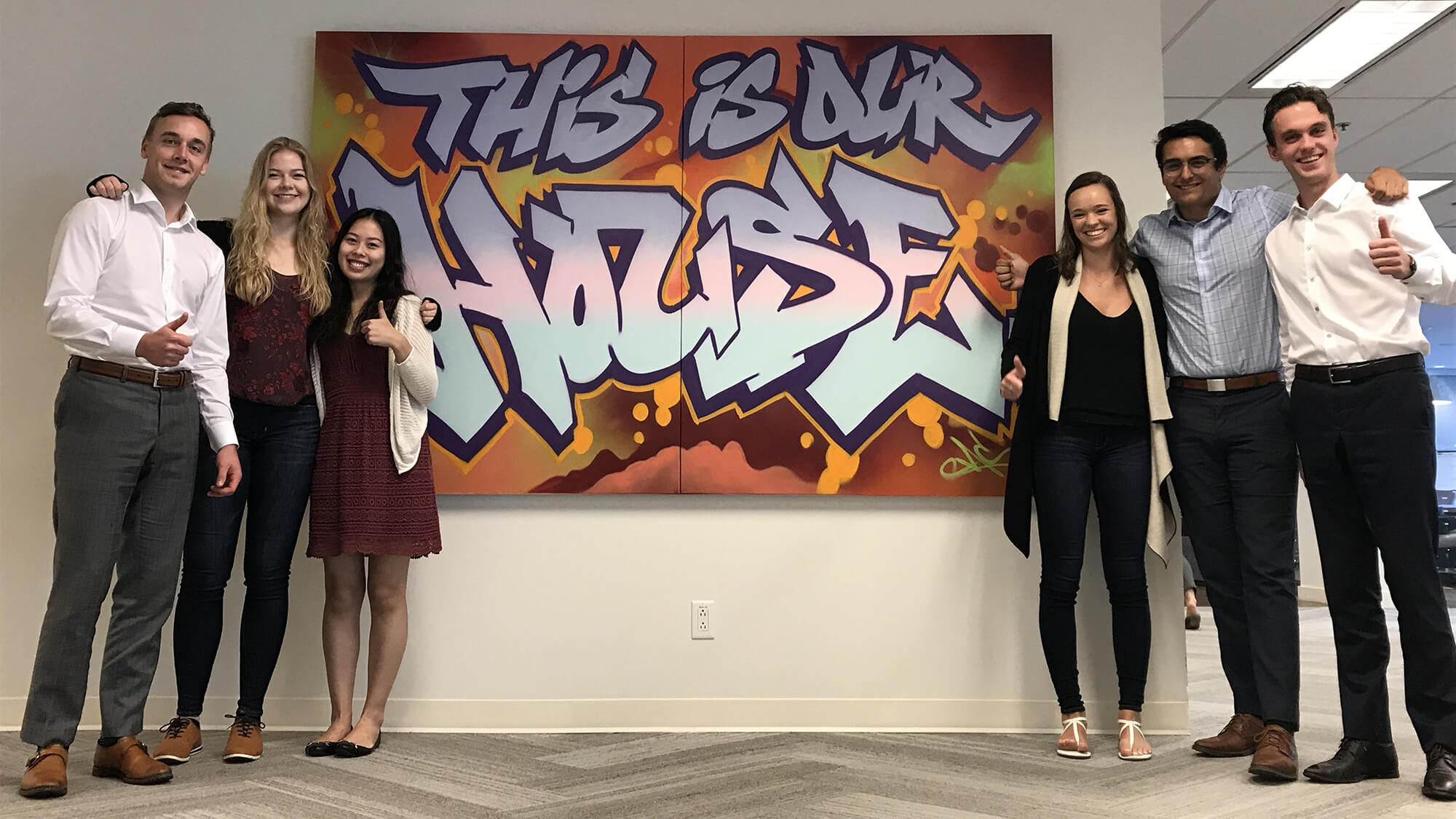 Six of Dream's Summer Co-op students posing happily beside a sign that reads