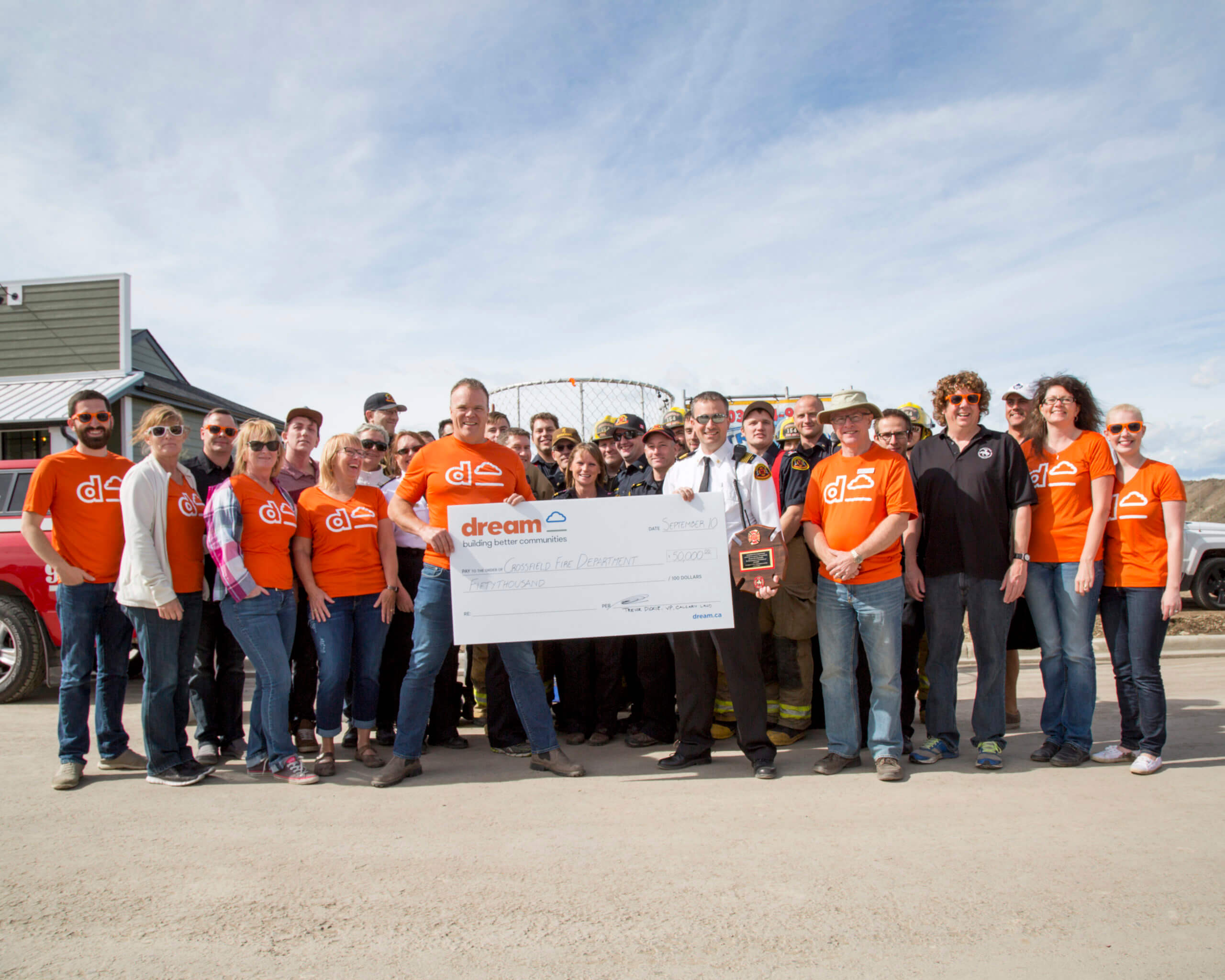Dream employees volunteering holding up charitable donation cheque.