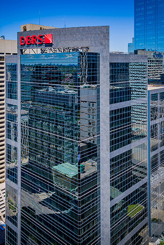 cropped aerial image of Dream Office's Adelaide Place with mirrored exterior and people crossing the street intersection.