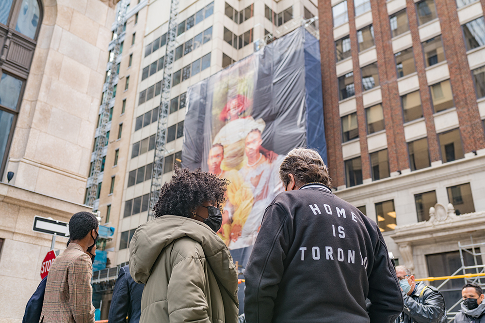 Mayor John Tory and Artist Jorian Charlton looking up at Jorian's photo applied to the side of a building on Bay Street in Toronto