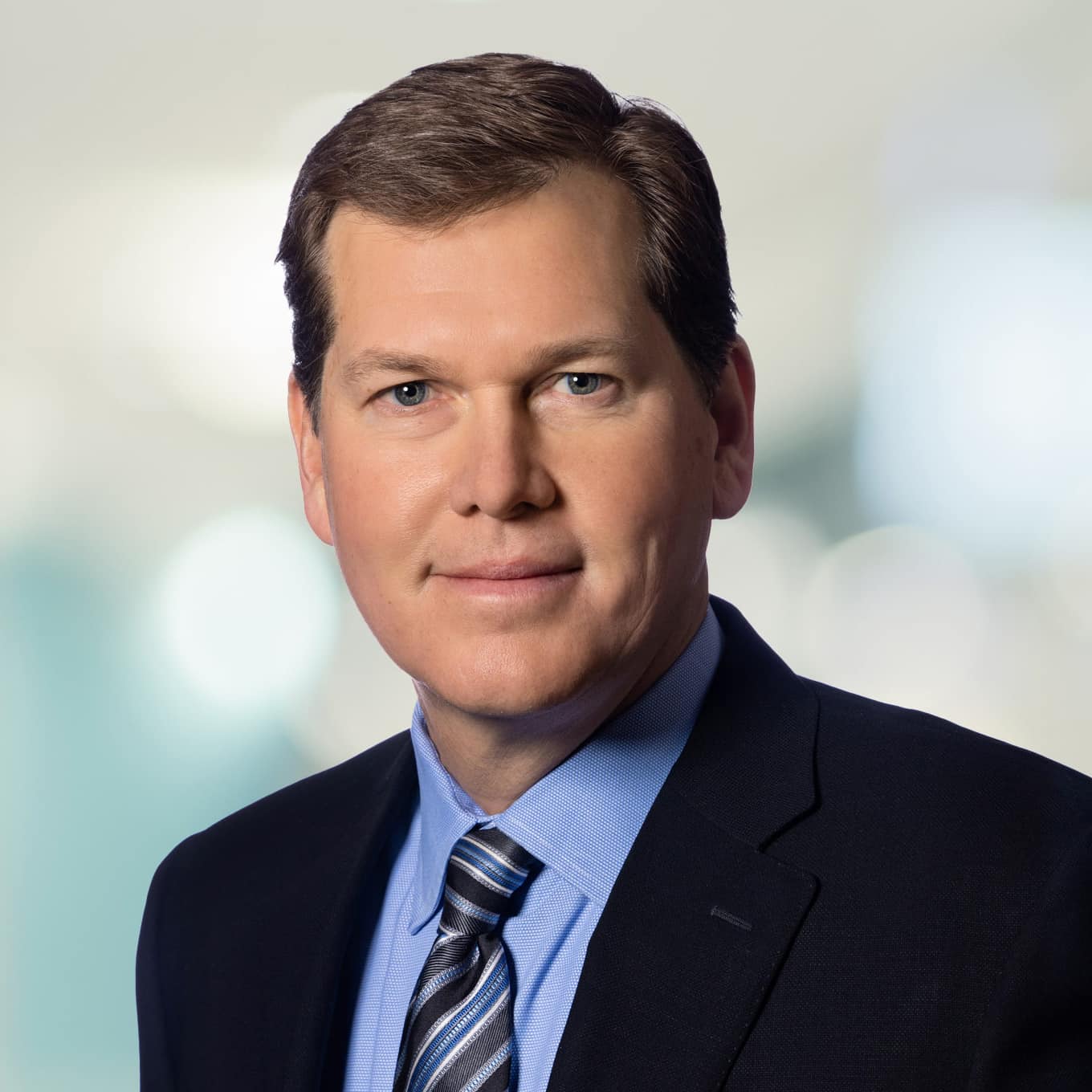 Headshot of Brian Pauls, CEO of Dream Industrial REIT, wearing a blue collard shirt, striped tie and black blazer