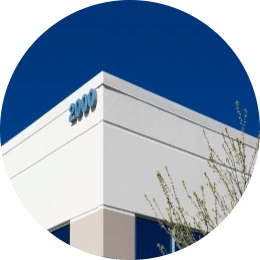 a close up of the top corner of an industrial building that is surrounded by a deep blue sky, the shite building has the numbers 2000 written in a soft blue tone