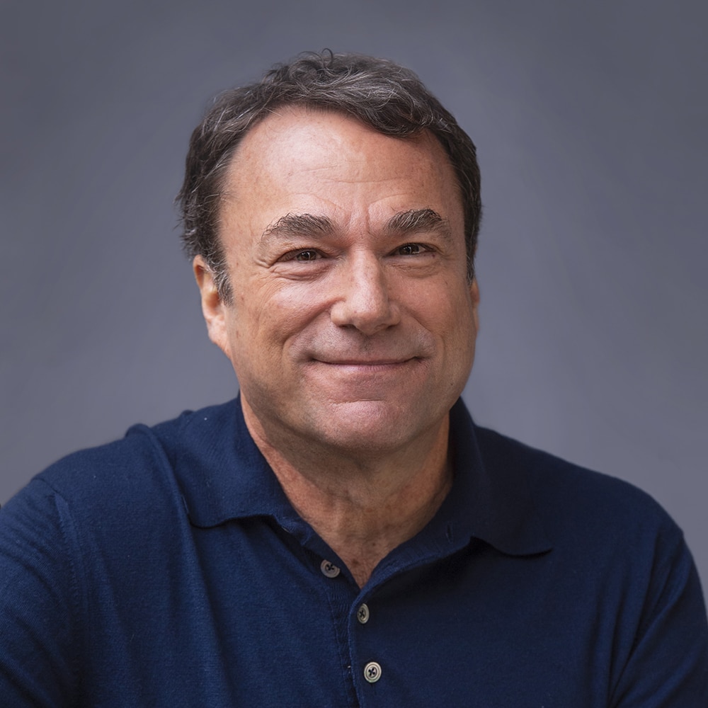 Smiling Headshot of Michael Cooper, President and CRO, wearing a blue button up shirt